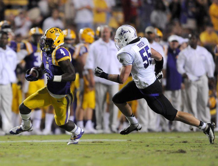 LSU senior running back Alfred Blue (4) runs past Furman sophomore Carl Rider (55) on Saturday night, Oct. 26, 2013 during the Tigers' 48-16 win against Furman in Tiger Stadium.