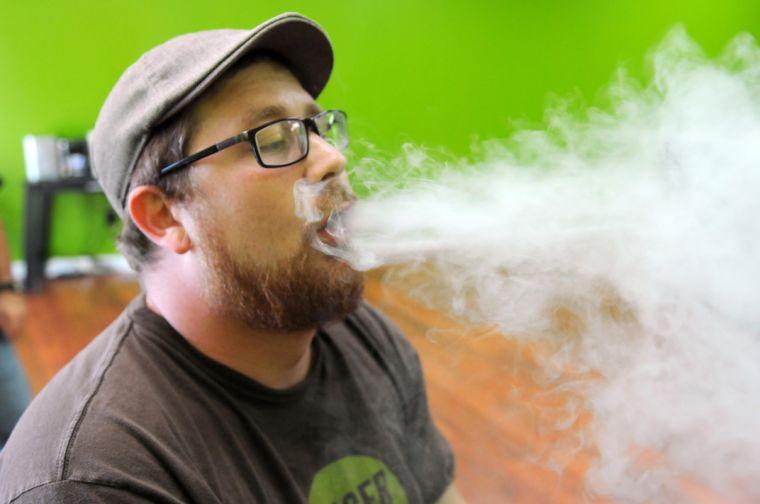 Cameron Kelley, manager of the Baton Rouge Smokecignals, exhales electronic cigarette vapor.