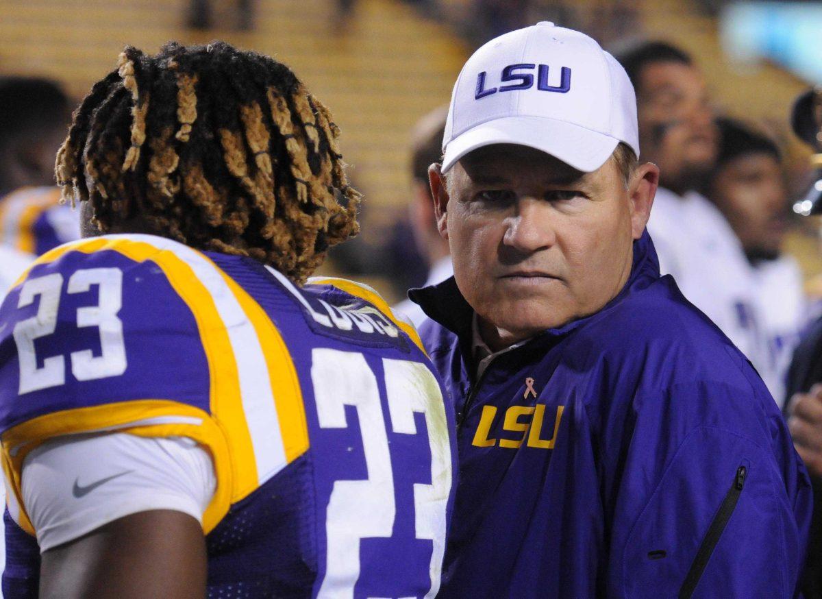 Les Miles and LSU sophomore Lamar Louis (23) exit the field Saturday night, Oct. 26, 2013 after the Tigers' 48-16 win against Furman in Tiger Stadium.