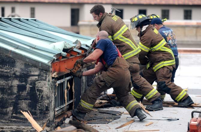 Firefighters try to remove the side of the roof of the Huey P. Long Fieldhouse on Thursday, October 17, 2013.