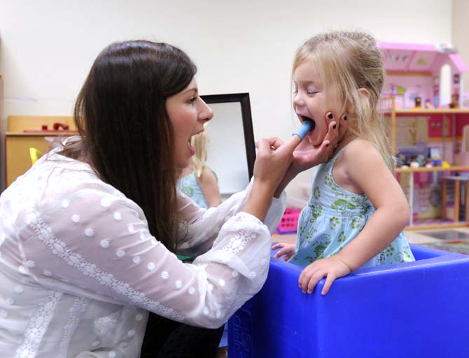 Speech Pathology graduate student Morgan Soike encourages Kate Worthington to move her tongue Monday, October 7, 2013 in Hatcher Hall.