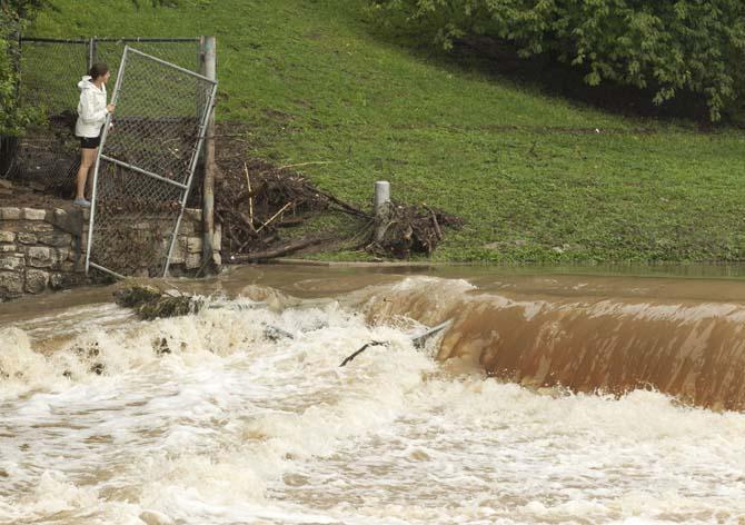 A woman looks at Barton Springs pool in Austin, Texas, after rain overnight flooded homes and cancelled the last day of the Austin City Limits Music Festival on Sunday Oct. 13, 2013. (AP Photo/Austin American-Statesman, Jay Janner)