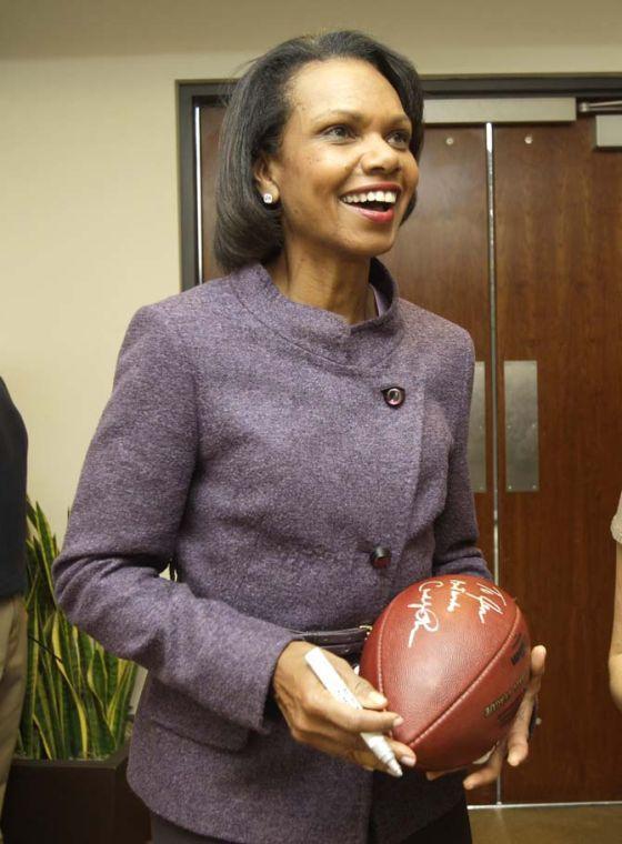 FILE - In this Oct. 10, 2010, file photo, former Secretary of State Condoleezza Rice laughs after autographing a football following her visit with the Cleveland Browns coaches and players at the team's NFL football training facility in Berea, Ohio. A person with direct knowledge of the process tells The Associated Press on Friday, Oct. 4, 2013, that Rice is expected to be part of the selection committee that will pick the teams for the College Football Playoff next year. The person spoke on condition of anonymity because the selection process is still ongoing. (AP Photo/Amy Sancetta, File)