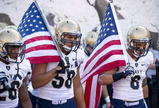 FILE - In this Sept. 7, 2013, file photo, from left, Navy's Marcus Thomas (26), Evan Palelei (58) and Wave Ryder (8) head onto the field at the start of an NCAA college football game against Indiana in Bloomington, Ind. The Defense Department said Tuesday, Oct. 1, 2013, that it has temporarily suspended all sports competitions at the service academies as a result of the partial government shutdown. The decision jeopardizes this weekend's football games , Air Force at Navy and Army at Boston College. (AP Photo/Doug McSchooler, File)