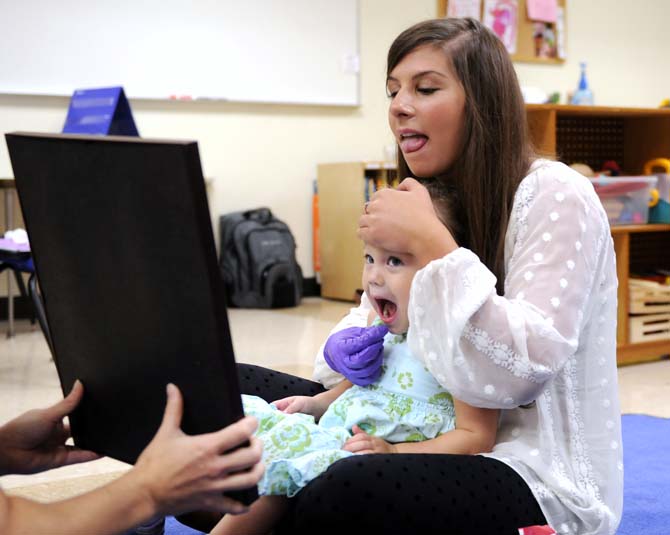 Speech Pathology graduate student Morgan Soike encourages Kate Worthington to move her tongue Monday, October 7, 2013 in Hatcher Hall.