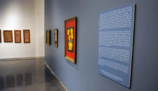 Framed pictures of self-taught folk artist Clementine Hunter hang in the LSU Museum of Art. Hunter's paintings often described her life working on a plantation. The Museum's exhibit runs through March 2013.