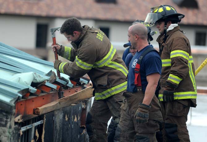 Firefighters try to remove the side of the roof of the Huey P. Long Fieldhouse on Thursday, October 17, 2013.