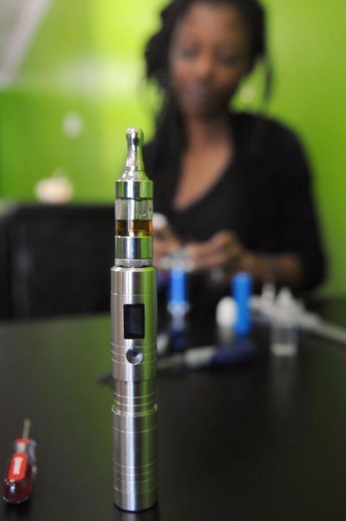 This futuristic silver cylinder is an electronic cigarette with an in-house blend of juices. In the background, Novelle Gibson puts a wick into the rebuildable atomizer of an electronic cigarette.