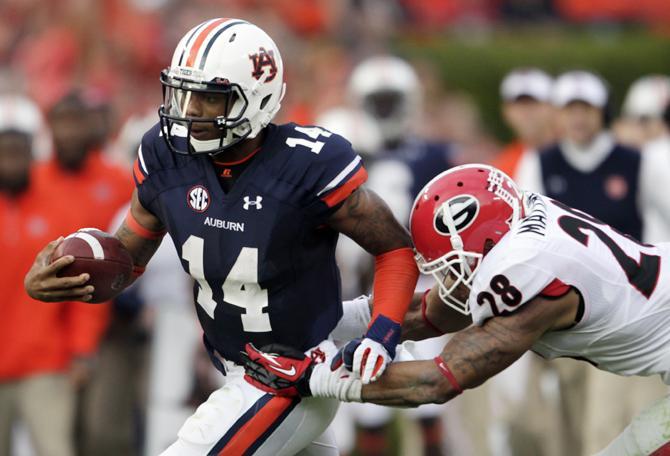 Auburn quarterback Nick Marshall (14) runs out of the tackle of Georgia safety Tray Matthews (28) during the first half of an NCAA college football game in Auburn, Ala., Saturday, Nov. 16, 2013. (AP Photo/Jay Sailors)