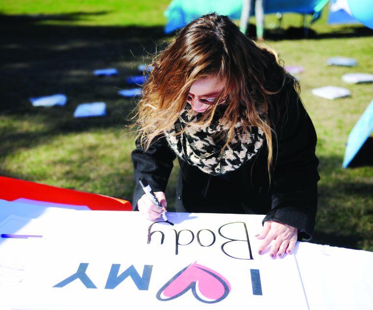 Mandie Tracy writes a body affirmation Wednesday, November 13, 2013 at the Southern Smash event on the Parade Grounds.