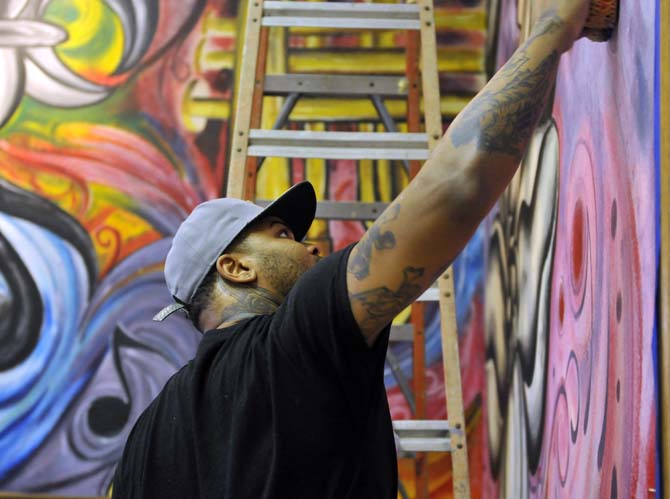 Baton Rouge artist Jiggy Johnson works on a mural on Tuesday, November 5, 2013 for the front entrance of what will be Triumph Kitchen.