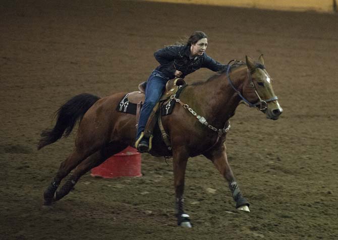 A female rider goes as fast as she can after riding around the three barrels Thursday, Nov. 21, 2013, during the Block and Bridle rodeo in the LSU Parker Coliseum.