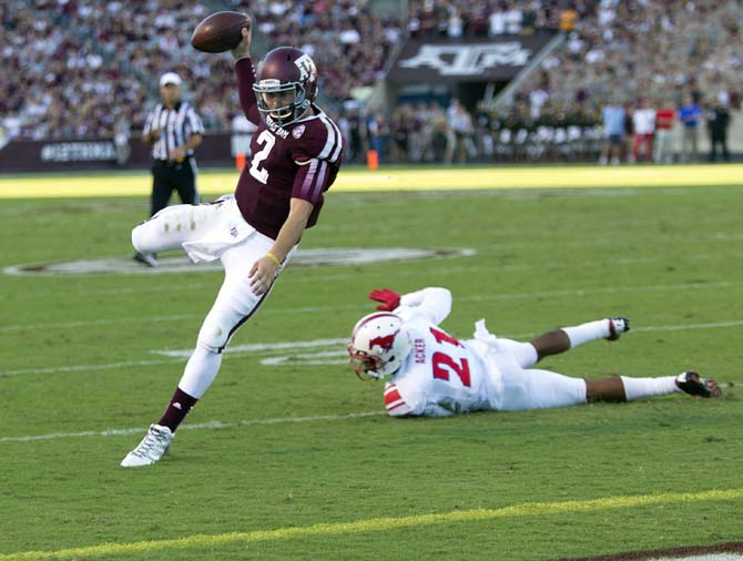 FILE - In this Sept. 14, 2013, file photo, Texas A&amp;M quarterback Johnny Manziel (2) rushes for a 7 yard touchdown as he avoids the tackle of SMU defensive back Kenneth Acker (21) during the first quarter of an NCAA college football game in College Station, Texas. Manziel has put up eye-popping numbers similar to and in some cases better than he did a year ago, but most polls don't have him favored to join Archie Griffin as the second two-time Heisman winner. (AP Photo/Bob Levey, File)