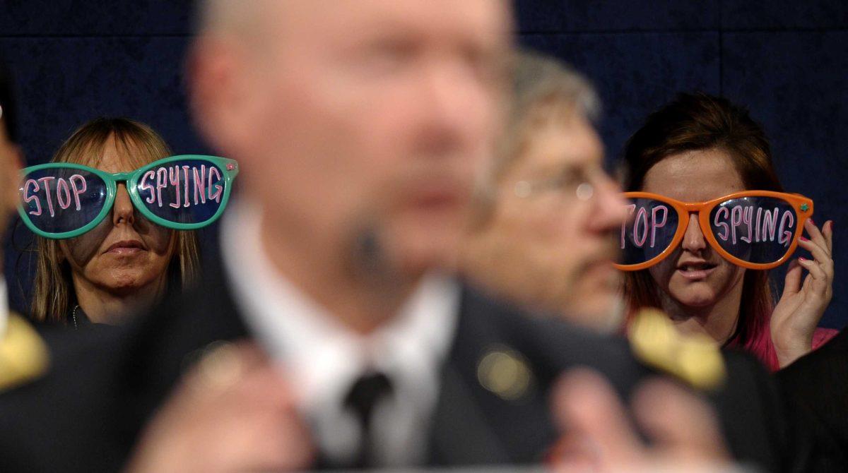 Protestors, including CodePink co-founder Medea Benjamin, left, listen as National Security Agency Director Gen. Keith Alexander, center, testifies on Capitol Hill in Washington, Tuesday, Oct. 29, 2013, before the House Intelligence Committee hearing on potential changes to the Foreign Intelligence Surveillance Act (FISA). Faced with anger over revelations about U.S. spying at home and abroad, members of Congress suggested Tuesday that programs the Obama administration says are needed to combat terrorism may have gone too far. (AP Photo/Susan Walsh)