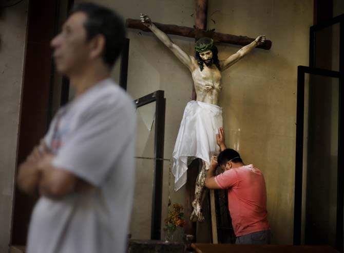 A Filipino man prays on a statue of Jesus Christ prior to a Mass at Santo Nino church, which was damaged by Typhoon Haiyan in Tacloban, Philippines, Sunday, Nov. 17, 2013. Typhoon Haiyan, one of the most powerful storms on record, hit the country's eastern seaboard Nov. 8, leaving a wide swath of destruction. (AP Photo/Dita Alangkara)