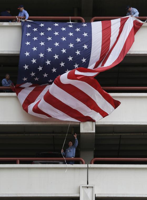 In preparation for Veteran's Day, workers hang a three-story long U.S. Flag off a parking garage, Thursday, Nov. 7, 2013, in downtown San Antonio. Veteran's Day is Monday. (AP Photo/Eric Gay)