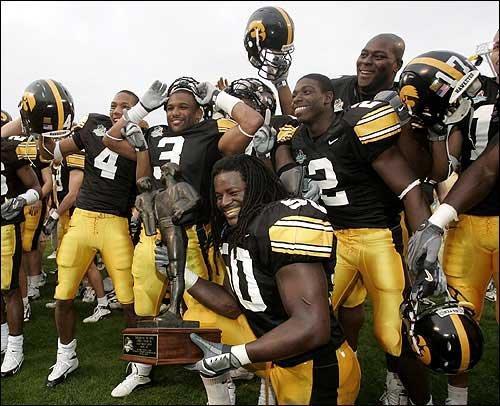 Iowa's George Lewis holds the Capital One Bowl trophy while celebrating with teammates. The 11th-ranked Hawkeyes scored on the last play of the game to defeat No. 12 LSU, 30-25, Saturday in Orlando, Fla.