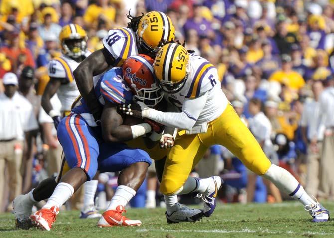 LSU senior linebacker Lamin Barrow (18) and senior safety Craig Loston (6) tackle Florida junior running back Mack Brown (33) Saturday, Oct. 12, 2013 during the Tigers' 17-6 victory against the Gators in Tiger Stadium.