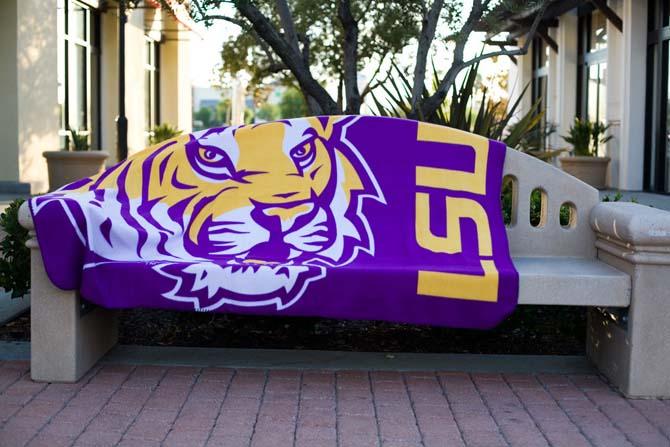 An LSU-themed blanket drapes over a bench on campus.