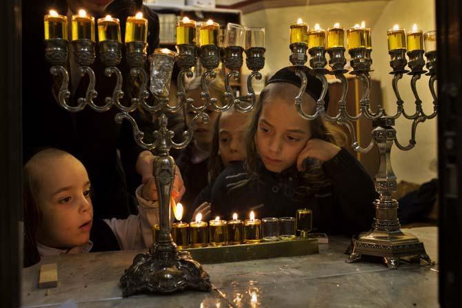 Members of the Kraus family, a Jewish ultra-orthodox family, light candles during the Jewish holiday of Hanukkah in Jerusalem's Mea Shearim neighborhood, Monday, Dec. 2, 2013. (AP Photo/Bernat Armangue)