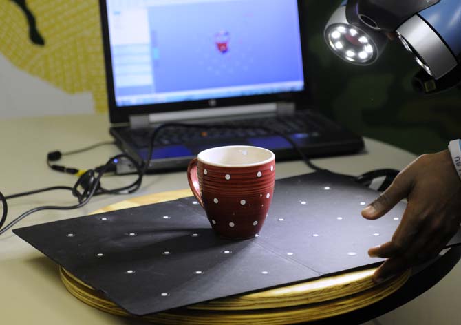 A mug gets scanned to create a 3D rendition of it on the computer screen on Tuesday, Dec. 3, 2013, in the CxC studio in the main art building.