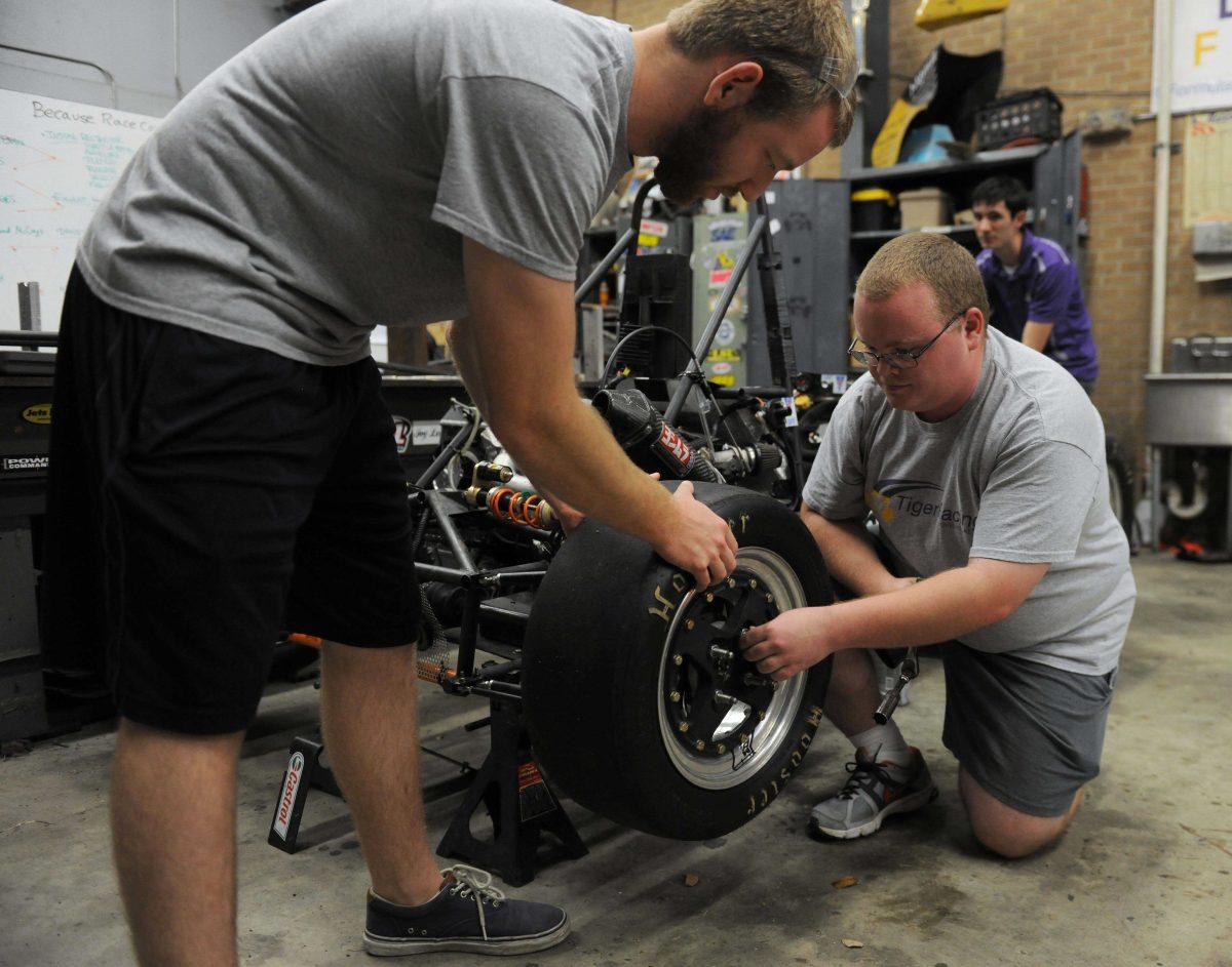 Mechanical engineering senior Joe Hollier&#160;and mechanical engineering sophomore Eric Rohli change the tire on the car for Team Tiger Racing Wednesday, Dec. 4, 2013 in the LSU Mechanical Engineering Shop.