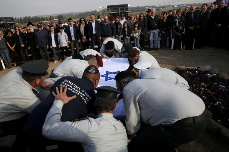 Israeli army officers lower the coffin of former Israeli Prime Minister Ariel Sharon into the grave during his funeral during his funeral near Sycamore Farm, Sharon's residence in southern Israel, Monday, Jan. 13, 2014. Sharon was laid to rest Monday at his ranch in southern Israel as the nation bid a final farewell to one of its most colorful and influential leaders &#8212; a man venerated by supporters as a warrior and statesman but reviled in the Arab world as a war criminal.(AP Photo/Baz Ratner, Pool)