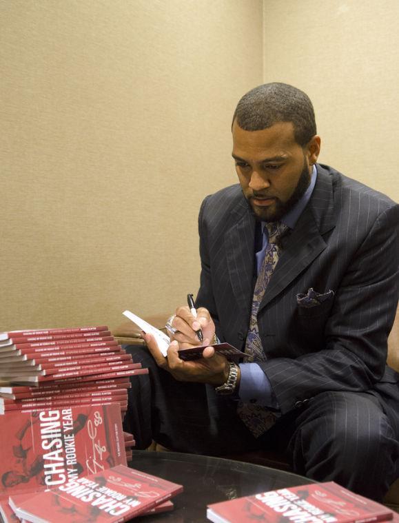 Michael Clayton, former LSU football player, signing his book "Chasing My Rookie Year" and adding personal notes to each individual inside cover for his fans.