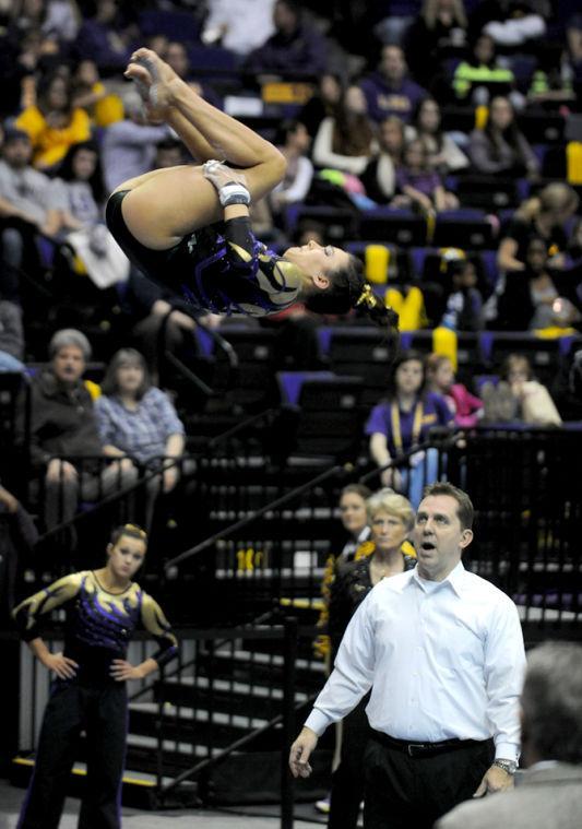 LSU Gymnist, Jessica Savona, coming out of her bar routine while Associate Head Coach, Jay Clark, watches at the LSU vs Auburn Gym Meet on 1.25.14 in the PMAC.