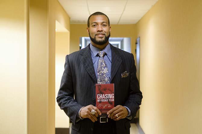 Former LSU football player, Michael Clayton, standing while holding his book "Chasing My Rookie Year" before an interview followed by a book signing on 1/16/14.