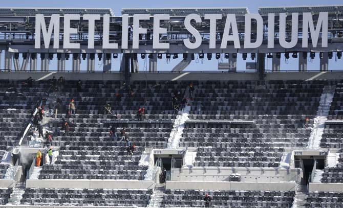 Workers shovel snow off the seats at MetLife Stadium as crews removed snow ahead of Super Bowl XLVIII following a snow storm, Wednesday, Jan. 22, 2014, in East Rutherford, N.J. Super Bowl XLVIII, which will be played between the Denver Broncos and the Seattle Seahawks on Feb. 2, will be the first NFL title game held outdoors in a city where it snows. (AP Photo/Julio Cortez)