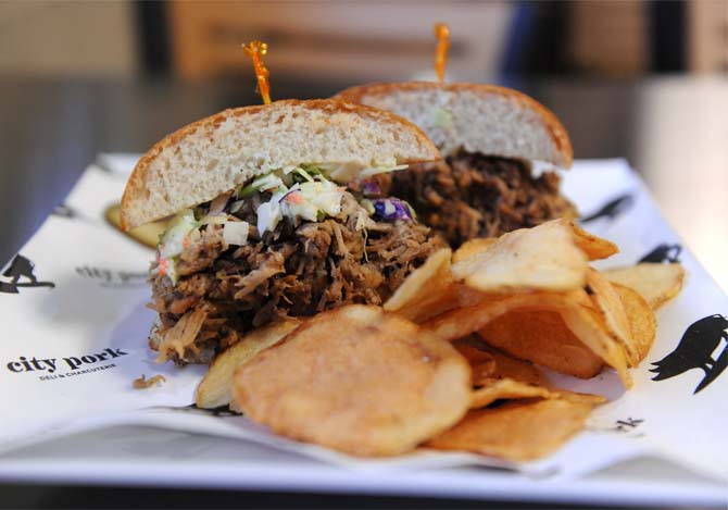 A 17-hour smoked pork shoulder sandwich topped with Carolina-style BBQ sauce and cole slaw on a brioche bun, known as the Big Pig, is one of the food items on City Pork's menu.