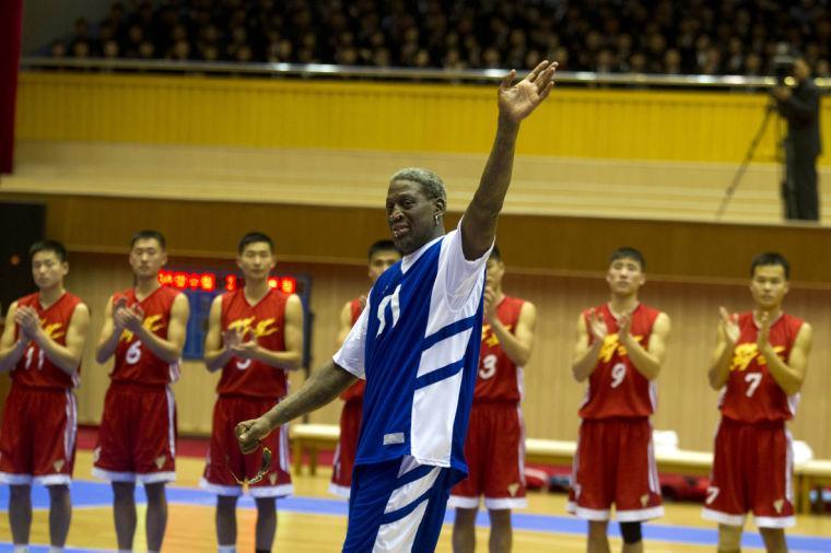 Dennis Rodman waves to North Korean leader Kim Jong Un, seated above in the stands, after singing Happy Birthday to Kim before an exhibition basketball game with U.S. and North Korean players at an indoor stadium in Pyongyang, North Korea on Wednesday, Jan. 8, 2014. (AP Photo/Kim Kwang Hyon)