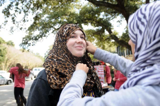 A member of the Muslim Student Association puts a hijab on psychology freshman Rebecca Doell during World Hijab Day on Friday, Feb. 7, 2014 in Free Speech Plaza.