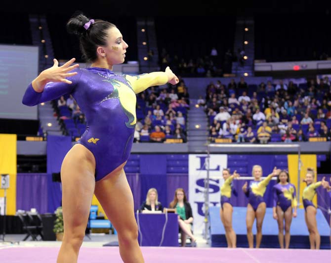 LSU junior all-around gymnast Rheagan Courville throws an arrow during her floor routine Friday, Feb. 28, 2014 as her teammates mimic her during the Tigers' 198.050-194.825 victory against Missouri at the PMAC.