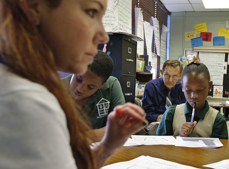 Principal Scott Steckler, rear, observes fourth-grade teacher Lora Johnson on Oct. 23 as she works with her students at George Cox Elementary in Gretna, La. With a grading sheet in hand, Steckler is complying with the latest of Louisiana&#8217;s education reform efforts to play out in public schools. Half of the high-stakes evaluation is based on classroom observation. (AP Photo/The Times-Picayune,Ted Jackson)