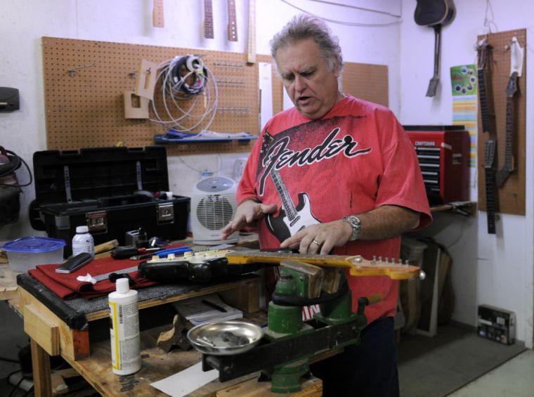 Tim Lawson places an electric guitar on the shop table for repair Friday afternoon, Feb. 7, 2014 at Tim's Guitar Repair and Workshop.