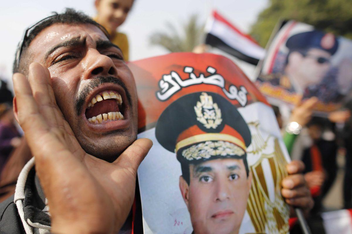 An Egyptian man holds a poster of Egyptian Defense Minister Gen. Abdel-Fattah el-Sissi with Arabic that reads, "we authorize you," as he chants slogans on a street leading to Tahrir Square, the epicenter of the 2011 uprising in Cairo, Egypt, Saturday, Jan. 25, 2014. Demonstrators began gathering Saturday in Egypt's Tahrir Square to mark the third anniversary of the start of its 2011 revolution, following a spate of bombings claimed by militants. (AP Photo/Hassan Ammar)