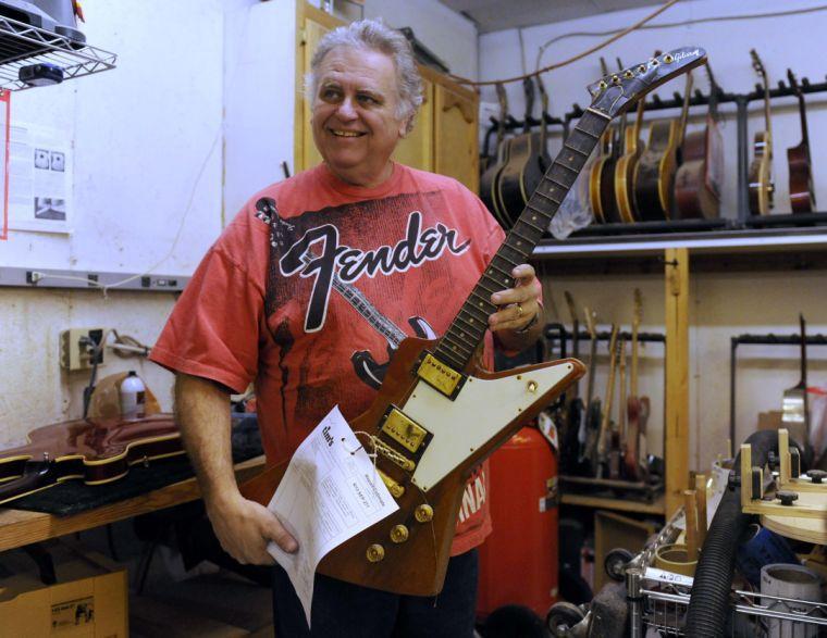 Tim Lawson holds a guitar belonging to blues musician Chris Thomas King on Friday afternoon, Feb. 7, 2014 at Tim's Guitar Repair and Workshop.