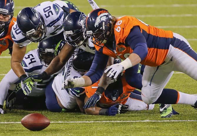 Seattle Seahawks' K.J. Wright (50), Chris Clemons (91) and Denver Broncos' Zane Beadles (68) dive after a fumble by the Broncos' Knowshon Moreno during the first half of the NFL Super Bowl XLVIII football game Sunday, Feb. 2, 2014, in East Rutherford, N.J. Beadles recovered the ball on the play. (AP Photo/Matt York)