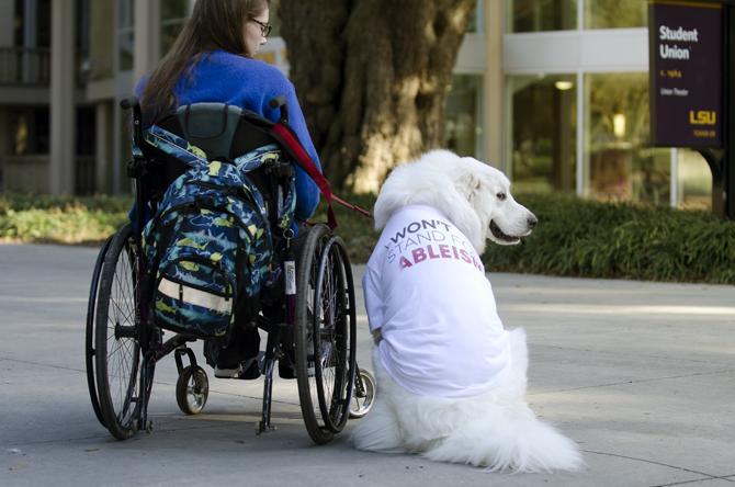 LSU Junior Alexandria Arceneaux, a food science major, next to Mishka, her guide dog, while wearing his "I Won't Stand For..." t-shirt stamped with "Ableism".