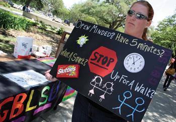 Jennifer Fleming, general studies senior and vice president of LGBT, displays a poster Monday morning encouraging a quad walk holding hands with someone of the same sex for five minutes.