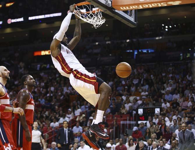 Washington Wizards players Marcin Gortat (4) and Martell Webster (9) watch as Miami Heat's LeBron James (6) dunks during the first half of an NBA basketball game in Miami, Monday, March 10, 2014. (AP Photo/J Pat Carter)