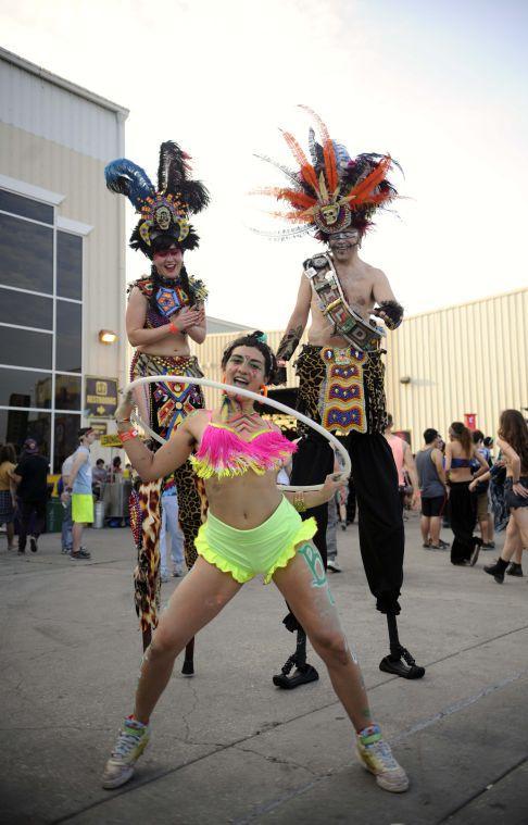 A couple on stilts watch as a woman hula hoops Saturday, March 22, 2014 duringt Buku Music + Art Project at Mardi Gras World in New Orleans.