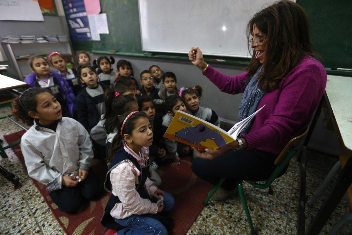 In this picture taken on Wednesday, March 5, 2014, Lebanese teacher Rajaa Bshara, right, reads a story for Syrian refugee students at a mixed Lebanese-Syrian students classroom at a Lebanese public school in Beirut, Lebanon. More than 2 million of those who should be in school remain in Syria, where classrooms have been bombed, used as shelters or turned into military barracks. Another 300,000 Syrian children don&#8217;t attend school in Lebanon, along with some 93,000 in Jordan, 78,000 in Turkey, 26,000 in Iraq and 4,000 in Egypt, UNICEF officials in Geneva said. Those numbers likely are higher, as UNICEF can&#8217;t count the children whose parents didn&#8217;t register with the United Nations refugee agency. (AP Photo/Hussein Malla)