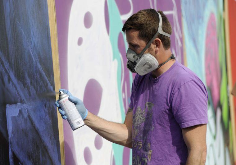 An artist paints his large wooden canvas during Buku Music + Art Project on Friday, March 21, 2014 at Mardi Gras World in New Orleans.