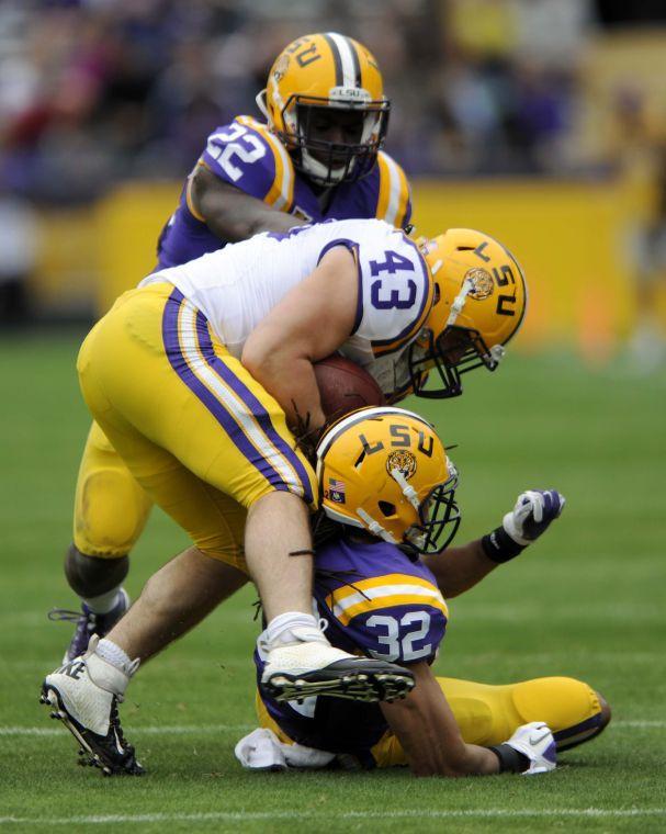 LSU junior linebacker Ronnie Feist (22) and LSU junior cornerback Jalen Collins (32) tackle LSU senior fullback Connor Neighbors (43) on Saturday, April 5, 2014 during the white squad's 42-14 victory against the purple squad in the National L Club Spring Game in Tiger Stadium.