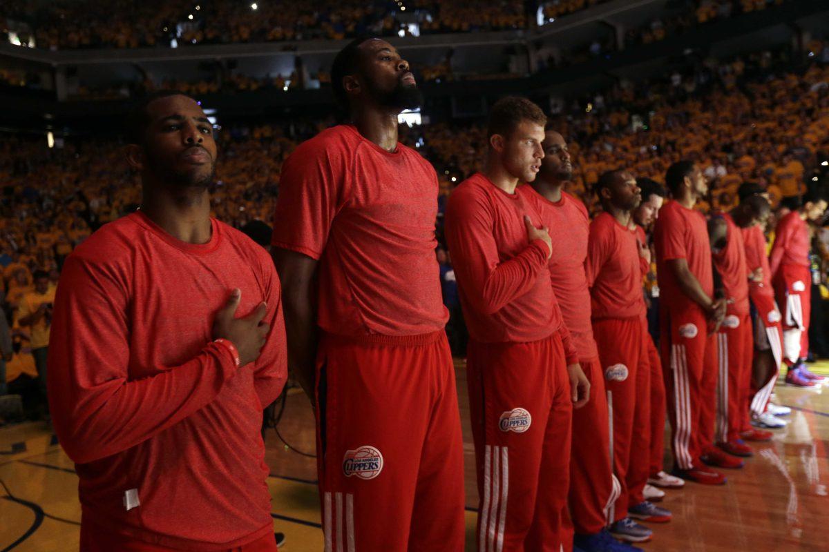 Members of the Los Angeles Clippers listen to the national anthem before Game 4 of an opening-round NBA basketball playoff series against the Golden State Warriors on Sunday, April 27, 2014, in Oakland, Calif. The Clippers chose not to speak publicly about owner Donald Sterling. Instead, they made a silent protest. The players wore their red Clippers' shirts inside out to hide the team's logo. (AP Photo/Marcio Jose Sanchez)