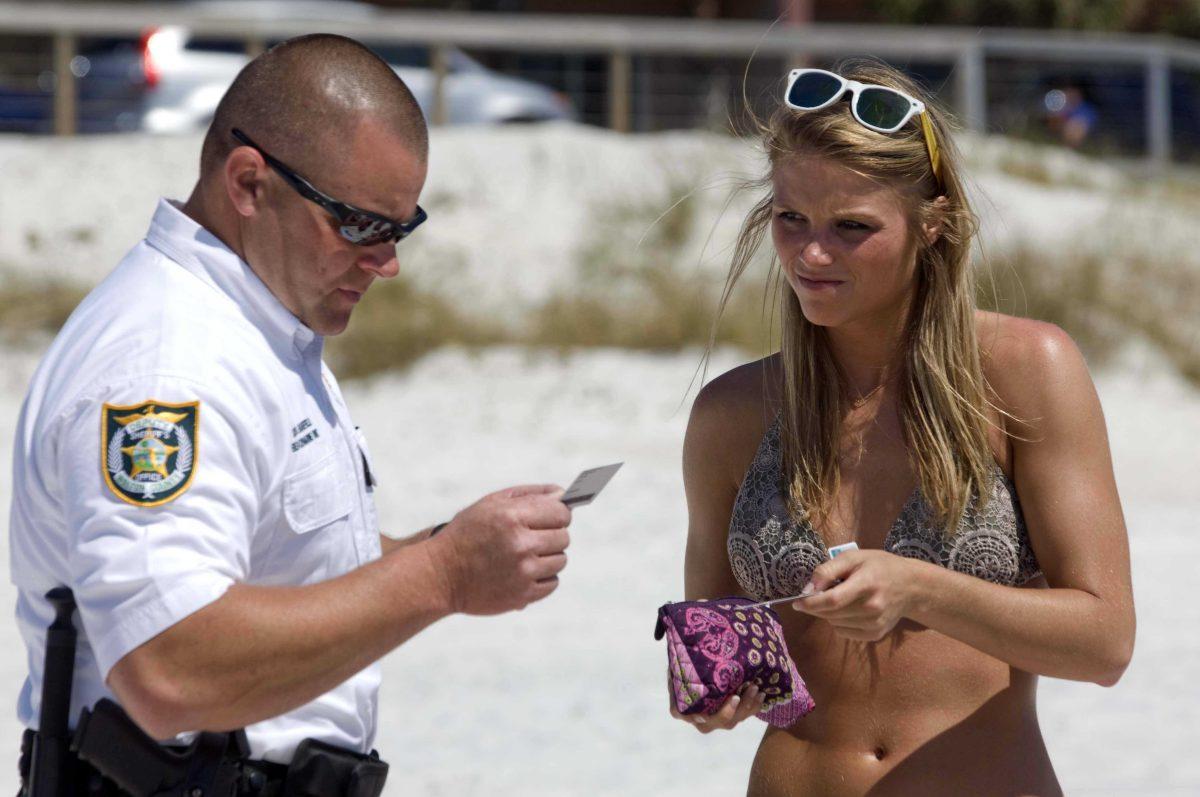 Walton County Deputy Sheriff Brad Barefield, left, checks the IDs of Jenna Harris and other spring breakers from Mississippi on the beach in South Walton County, Florida on Wednesday, March 13, 2013. As thousands of spring breakers descend on the beaches in this northwest Florida resort area, law enforcement personnel are making regular sweeps along the beaches looking for underage drinkers. Editor note: Jenna Harris and the others in her party were over 21 years old and not ticketed. (AP Photo/Northwest Florida Daily, Devon Ravine)