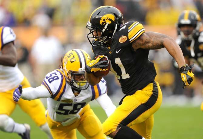 LSU senior linebacker Tahj Jones (58) attempts to tackle Iowa junior wide receiver Kevonte Martin-Manley (11) Wednesday, January 1, 2014 during the Tigers' 21-14 victory against the Hawkeyes in the Outback Bowl at Raymond James Stadium in Tampa, Florida.